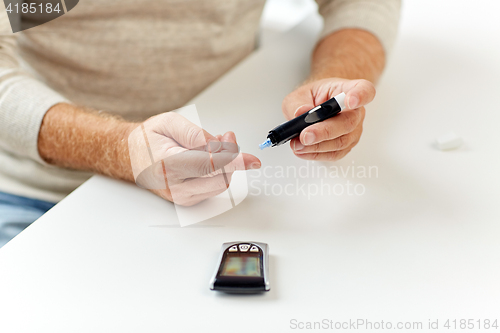 Image of senior man with glucometer checking blood sugar