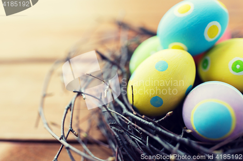 Image of close up of colored easter eggs in nest on wood