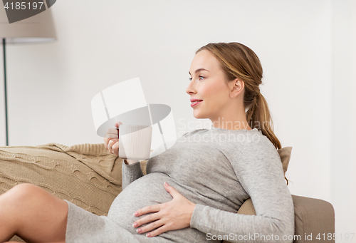 Image of happy pregnant woman with cup drinking tea at home