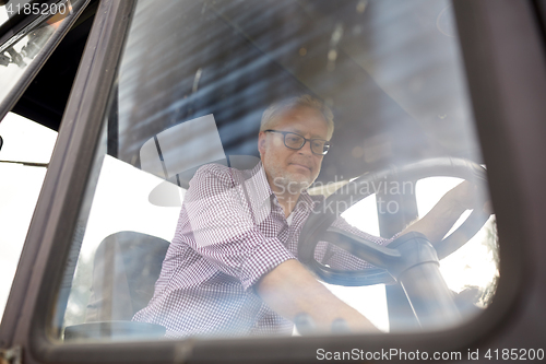 Image of senior man driving tractor at farm