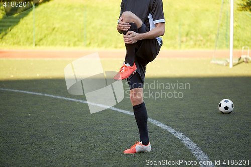 Image of soccer player stretching leg on field football