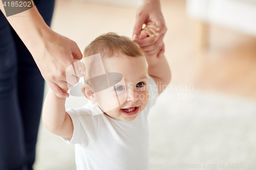 Image of happy baby learning to walk with mother help