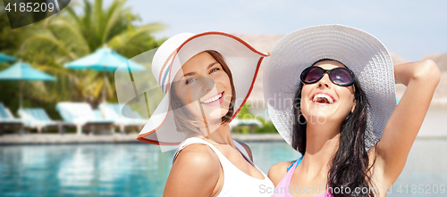 Image of smiling young women in hats on beach