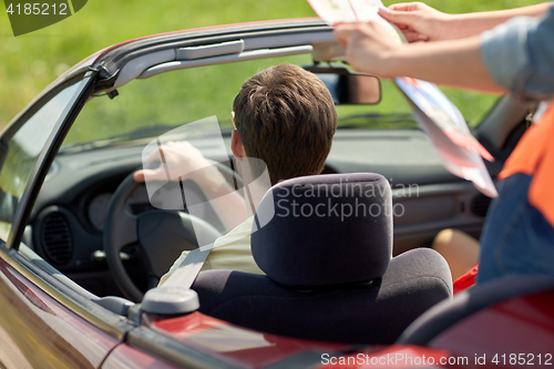 Image of happy friends with map driving in convertible car