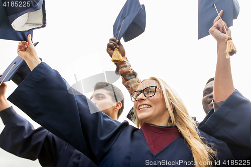 Image of happy students or bachelors waving mortar boards