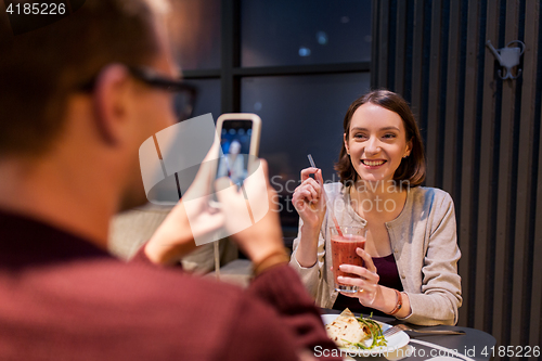 Image of happy couple with smartphone at vegan restaurant