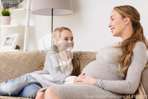 Image of happy pregnant woman and girl on sofa at home