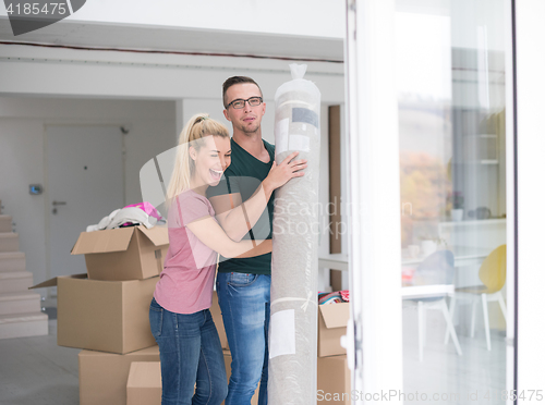 Image of couple carrying a carpet moving in to new home