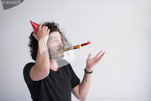 Image of Portrait of a man in party hat blowing in whistle