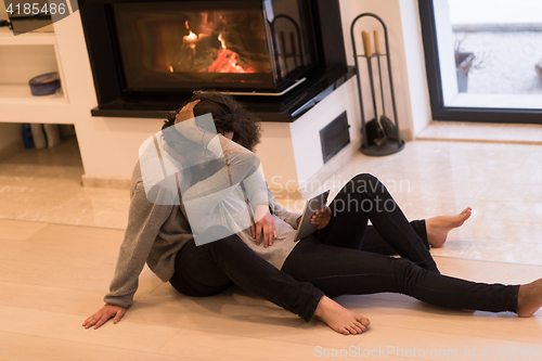 Image of multiethnic couple used tablet computer on the floor