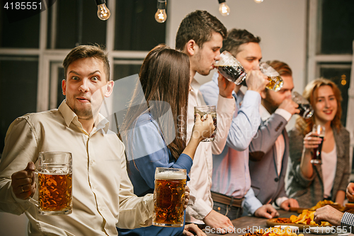 Image of Group of friends enjoying evening drinks with beer