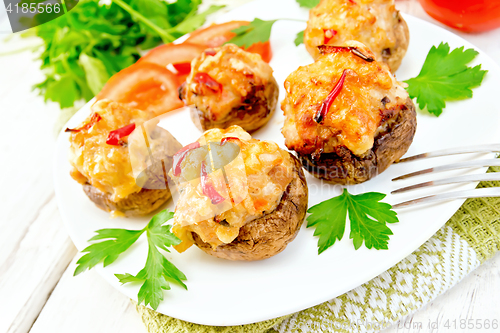 Image of Champignons stuffed with meat and peppers in plate on light boar