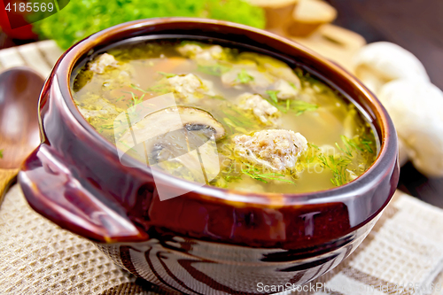 Image of Soup with meatballs and mushrooms in clay bowl on board