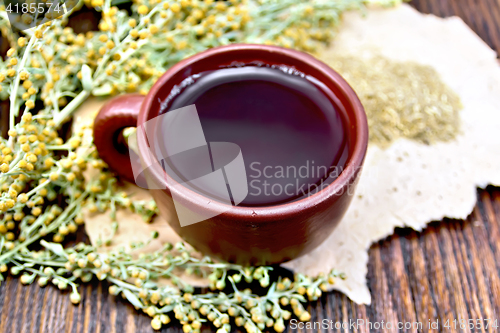 Image of Tea with wormwood in clay cup on rough paper