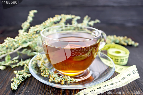 Image of Tea with wormwood in glass cup and meter on dark board