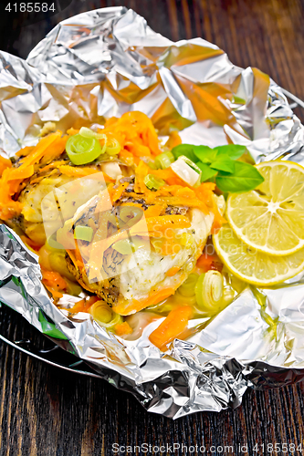 Image of Pike with leeks and carrots in foil on dark board