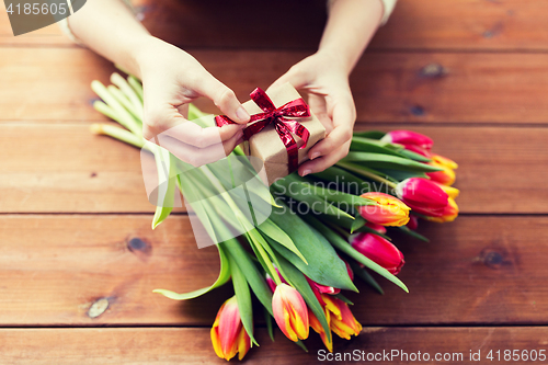 Image of close up of woman with gift box and tulip flowers