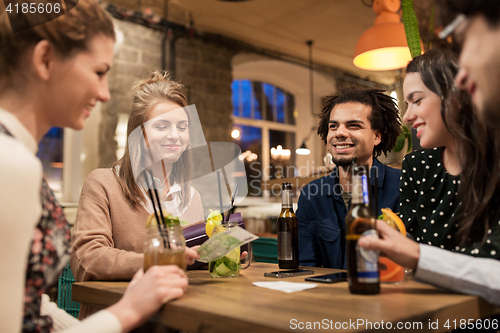 Image of friends with drinks, money and bill at bar