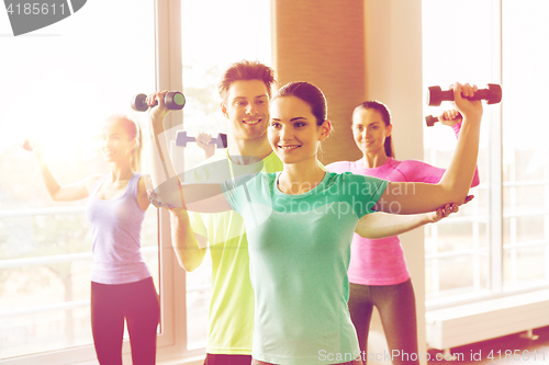 Image of group of smiling people exercising with dumbbells