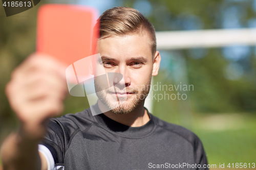 Image of referee on football field showing red card