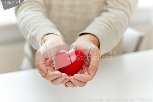 Image of close up of senior man with red heart in hands