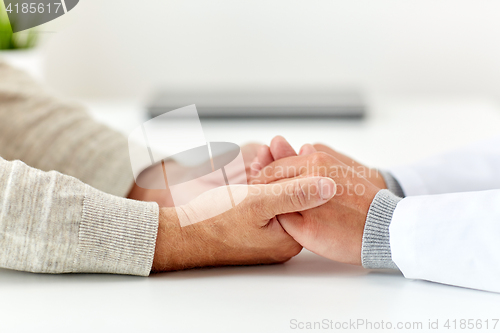 Image of close up of doctor holding old man hand