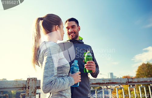 Image of smiling couple with bottles of water outdoors