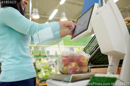 Image of woman weighing apples on scale at grocery store