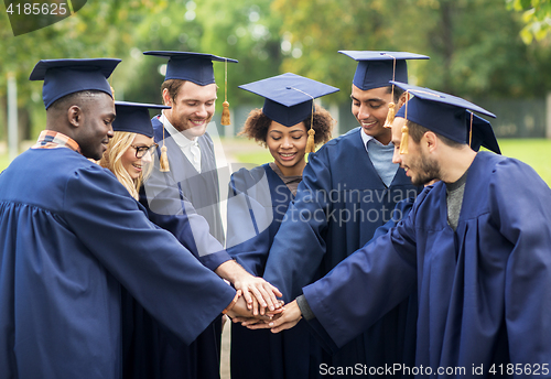 Image of happy students in mortar boards with hands on top