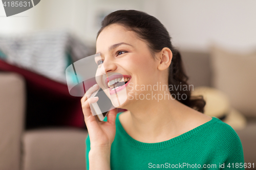 Image of happy woman calling on smartphone at home