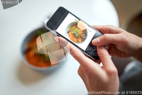 Image of woman with smartphone photographing food at cafe