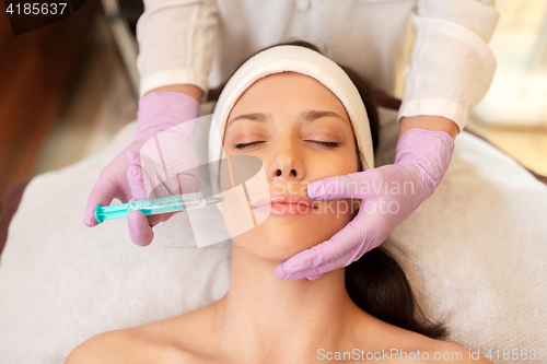 Image of beautician doing beauty injection to woman lips