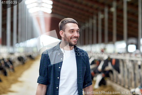 Image of man or farmer with cows in cowshed on dairy farm