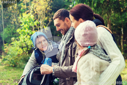 Image of happy family with backpacks and thermos at camp