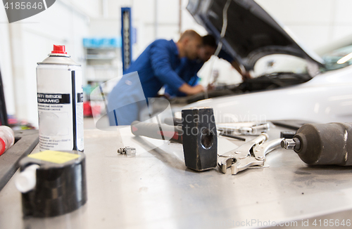 Image of working tools and men repairing car at workshop