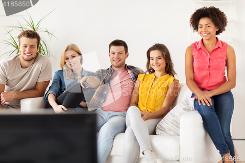 Image of happy friends with remote watching tv at home