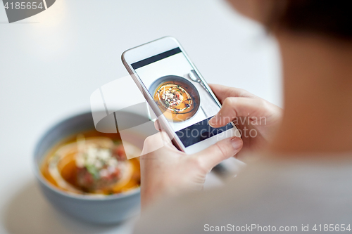 Image of woman with smartphone photographing food at cafe