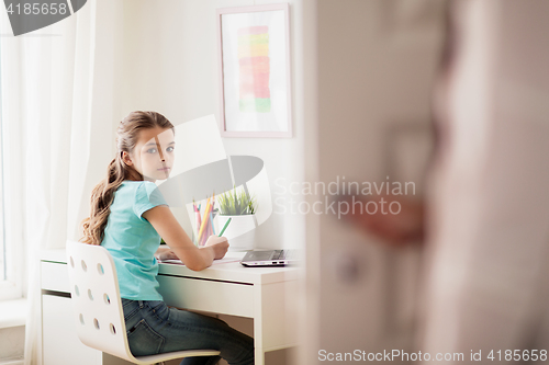 Image of girl with laptop writing to notebook at home