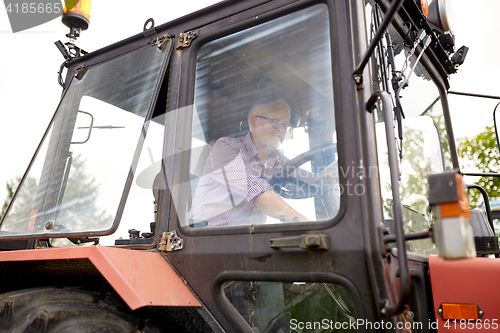Image of senior man driving tractor at farm