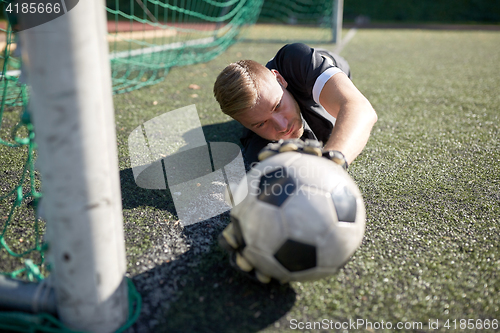 Image of goalkeeper with ball at football goal on field