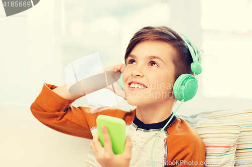 Image of happy boy with smartphone and headphones at home