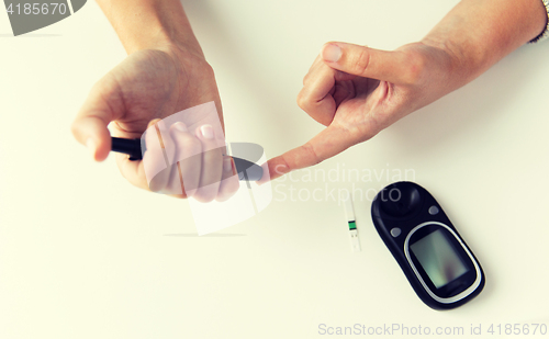 Image of close up of woman making blood test by glucometer