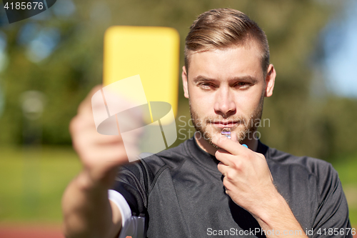 Image of referee on football field showing yellow card