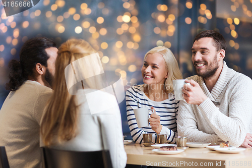 Image of happy friends drinking tea or coffee at cafe