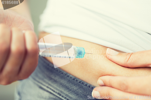 Image of close up of hands making injection by insulin pen