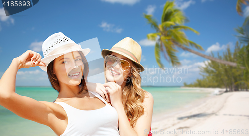 Image of happy young women in hats on summer beach