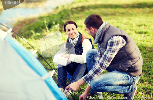 Image of happy couple setting up tent outdoors