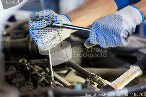 Image of mechanic man with wrench repairing car at workshop