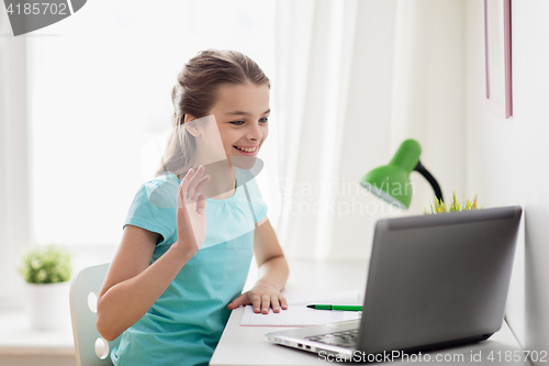 Image of happy girl with laptop waving hand at home