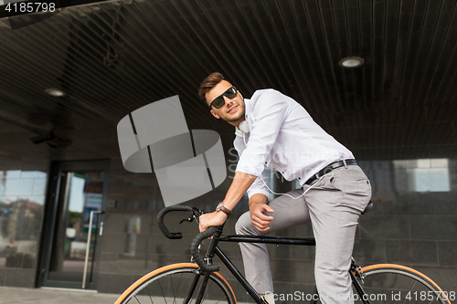 Image of man with bicycle and headphones on city street